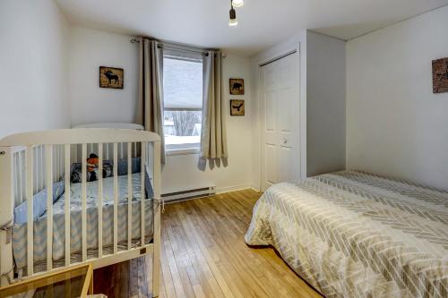 a baby bedroom with a crib and a window at L'Ancestrale en beauté dans le coeur de St-Raymond in Saint-Raymond