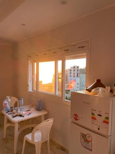 eine Küche mit einem Tisch, einem Kühlschrank und einem Fenster in der Unterkunft Mon rêve in Douar Chaïb Rasso