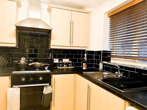 a kitchen with a sink and a stove top oven at Vista Lodge in Wythenshawe