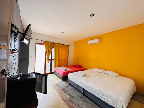 1 dormitorio con paredes amarillas, 1 cama y TV en Casa Coral Mahahual - Costa Maya en Mahahual