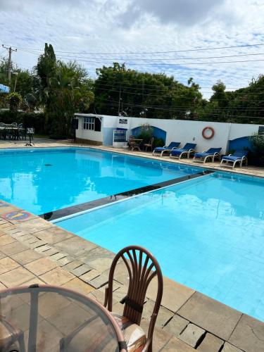 a large blue swimming pool with chairs around it at Sunrise Apartments-Nyali in Nyali