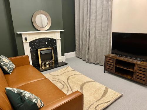 a living room with a couch and a fireplace at The Naunton Nook in Cheltenham
