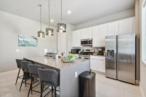 a kitchen with a large island with chairs and a refrigerator at Stunning New Condo Close to Disney World in Kissimmee