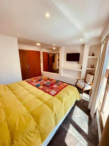 a bedroom with a large yellow bed and a chair at Peatonal Suites Paraná in Paraná