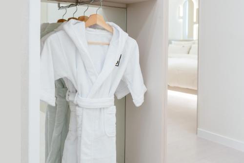 a white robe hanging on a rack in a bedroom at Pico Kids Pool Villa in Busan