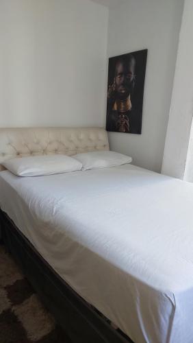 a bed with white sheets and a picture on the wall at Apartamento Copacabana vista lateral mar in Rio de Janeiro