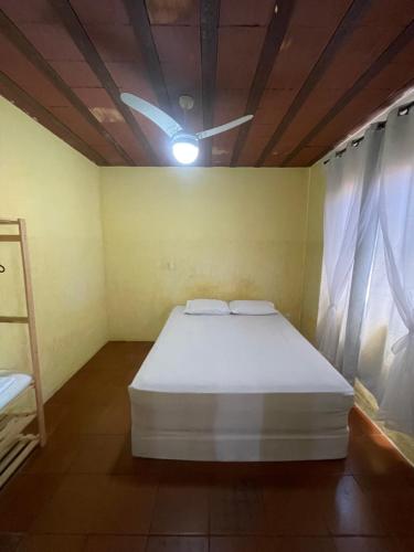 a bedroom with a white bed and a ceiling fan at Flat Maricá com ar-condicionado in Maricá