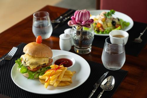 a table with two plates of food with a sandwich and fries at Sala Siem Reap Hotel in Siem Reap