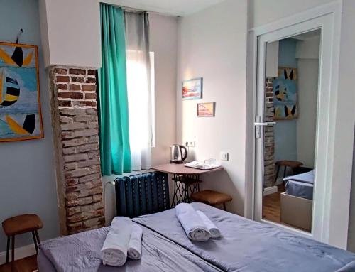Schlafzimmer mit einem Bett, einem Tisch und einem Fenster in der Unterkunft 9 Doors in Tbilisi City