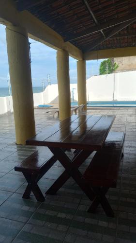 un tavolo in legno e una panca posti sotto un padiglione di Casa Beira Mar - Praia Icaraí - CE a Caucaia