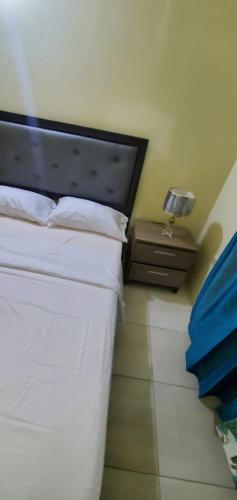 a bedroom with a white bed and a night stand at Finest Accommodation Phoenix Park Phase 1 Lot 74 Portmore St Catherine in Portmore