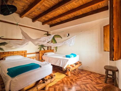 2 Betten in einem Zimmer mit Holzböden in der Unterkunft Hostel Coco Loco in Canoa