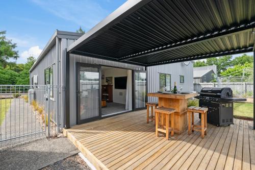 a patio with a grill and a deck with a house at The Tin Hut - Kinloch in Kinloch