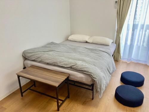 een bed in een kamer met een tafel en twee krukken bij GEビルAFUSO in Atsutabaru