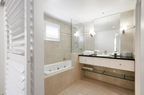 a bathroom with a tub and a sink and a mirror at Laguna on Hastings, Apartment 117, Noosa Heads in Noosa Heads