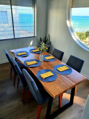 a dining room table with blue plates and yellow napkins at Ultimate Coastal Escape + Amazing Views in Caloundra