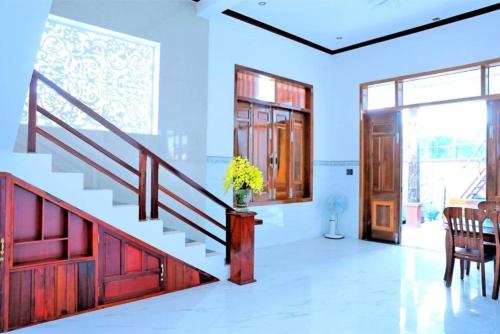 a living room with a staircase and a table and chairs at Nybipu Homestay in Phan Rang