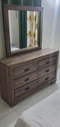 a wooden dresser with a mirror on top of it at Finest Accommodation Phoenix Park Phase 4 Lot # 1348 Portmore St Catherine in Portmore