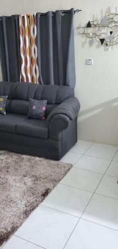a couch sitting in a living room with a curtain at Finest Accommodation Phoenix Park Phase 4 Lot # 1348 Portmore St Catherine in Portmore
