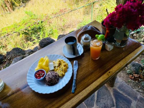 a plate of breakfast food on a wooden table at Eco-Lodge El Porvenir. in Santa Cruz