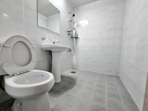 a white bathroom with a toilet and a sink at Wandonesia in Wando