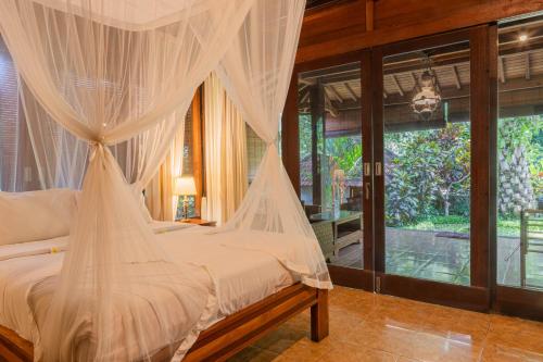 a bedroom with a bed with mosquito netting at Sari Bamboo Villas in Ubud