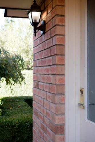 a light on a brick wall next to a door at Homely Unit Located Near the City with Parking and Wifi in Kings Meadows