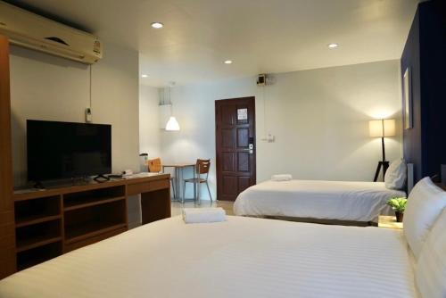 a hotel room with two beds and a flat screen tv at The View Residence in Bangkok