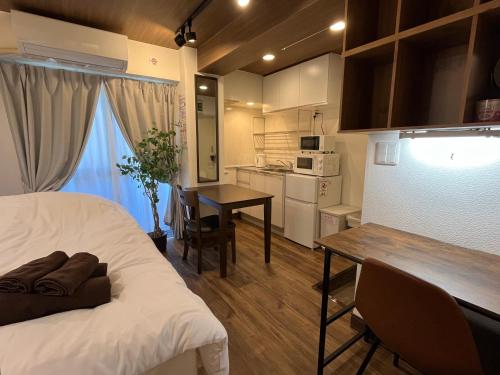 a room with a bed and a table and a kitchen at Cozy inn Oyama in Tokyo