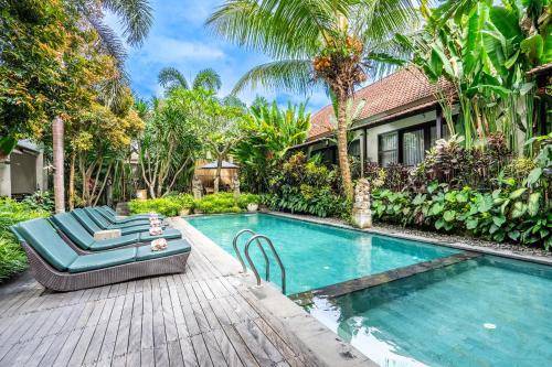 a swimming pool with a chaise lounge and a house at Meruhdani Boutique Hotel Ubud in Ubud