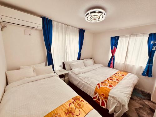 two beds in a room with blue curtains at Colorful House SKY TREE in Tokyo