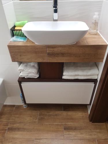 La salle de bains est pourvue d'un lavabo sur une étagère en bois et de serviettes. dans l'établissement Apartamenty Centrum Rynek, à Kielce
