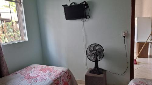 Habitación con ventilador, cama y TV. en Hostel Santa Luzia en Viçosa
