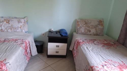 a small bedroom with two beds and a night stand at Hostel Santa Luzia in Viçosa