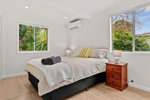 a bedroom with a bed and two windows at Mollymook Golden Sands in Narrawallee
