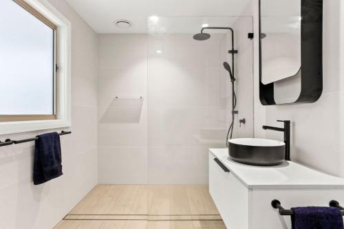 a white bathroom with a sink and a shower at Mollymook Golden Sands in Narrawallee