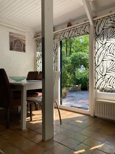 a dining room with a table and a sliding glass door at Gudrun 5 pers Equipped house with sauna. Dogs are welcome! in Anjum