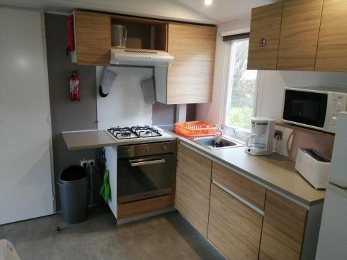 Il comprend une petite cuisine équipée d'une cuisinière et d'un évier. dans l'établissement mobil-home camping siblu, à Litteau