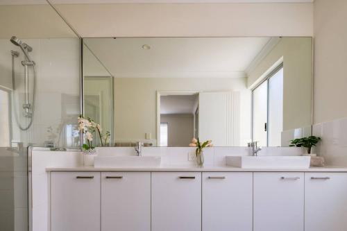 a bathroom with two sinks and a large mirror at Belmont Beauty - Relaxing Poolside Stay for Families in Perth