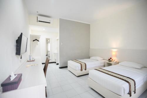 a hotel room with two beds and a television at Cakra Kusuma Hotel in Yogyakarta