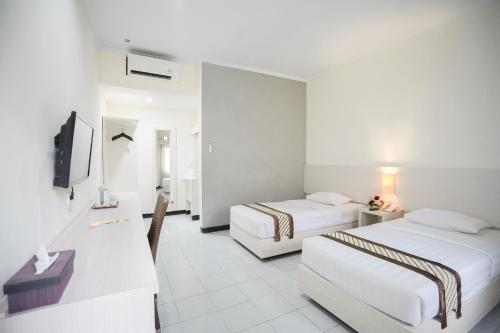 una camera d'albergo con due letti e una televisione di Cakra Kusuma Hotel a Yogyakarta