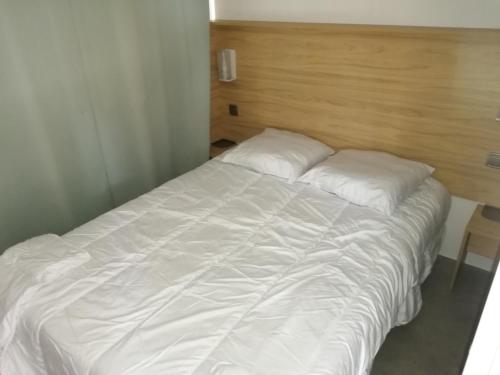 un lit avec des draps blancs et des oreillers dans une chambre dans l'établissement mobil-home camping siblu, à Litteau