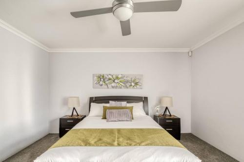a white bedroom with a bed and two lamps at Rivervale Retreat - Spacious Family Living in Perth