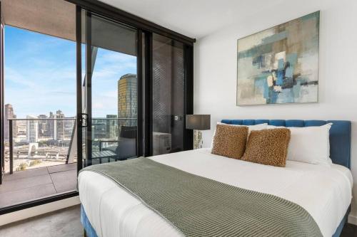 een slaapkamer met een groot bed en een groot raam bij Stylish & Central w Stunning City Views & Balcony in Melbourne