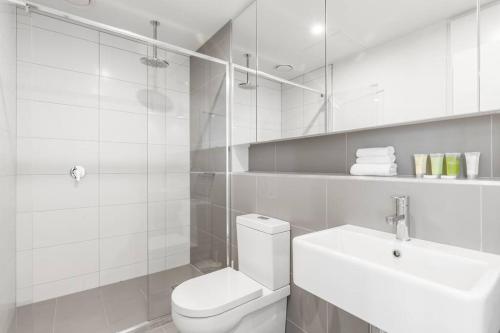 een witte badkamer met een toilet en een wastafel bij Stylish & Central w Stunning City Views & Balcony in Melbourne