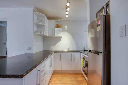 a kitchen with white cabinets and a refrigerator at Leafy Inner-city Nest near Lively Leederville in Perth