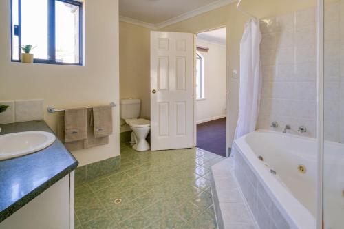 パースにあるBelmont Comfort - Central and Light-filled Stayの浴槽、洗面台、トイレを備えたバスルーム