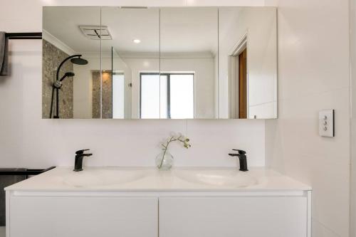 a white bathroom with a sink and a mirror at 'Karrinyup Villa' Lush Indoor-Outdoor Living in Perth