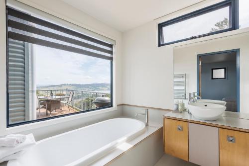 baño con bañera, lavabo y ventana en Armalong Winery Chalets, en Rosevears