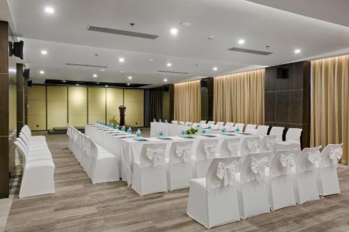a banquet hall with white tables and white chairs at Satya Da Nang Hotel Han Market in Da Nang